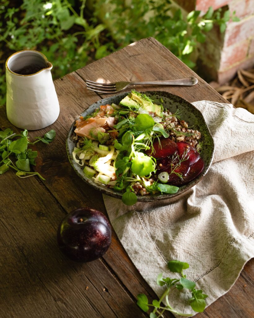 A Queen Garnet Plum + Smoked Salmon Scandi Bowl, on a wooden table