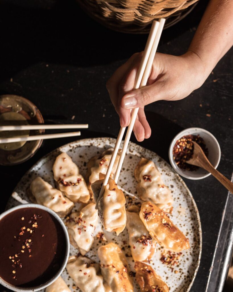 Chopsticks picking up dumplings, about to dip into Chinese Plum Sauce