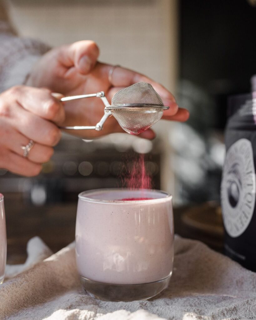 Australian Plum Powder being sprinkled atop a glass of Plum Collagen Mylk