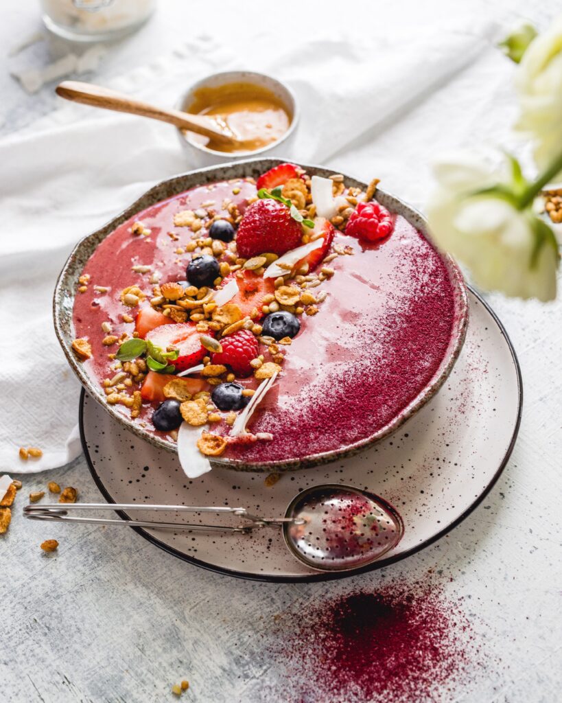 Plum Smoothie Bowl on a table with fresh fruit alongside